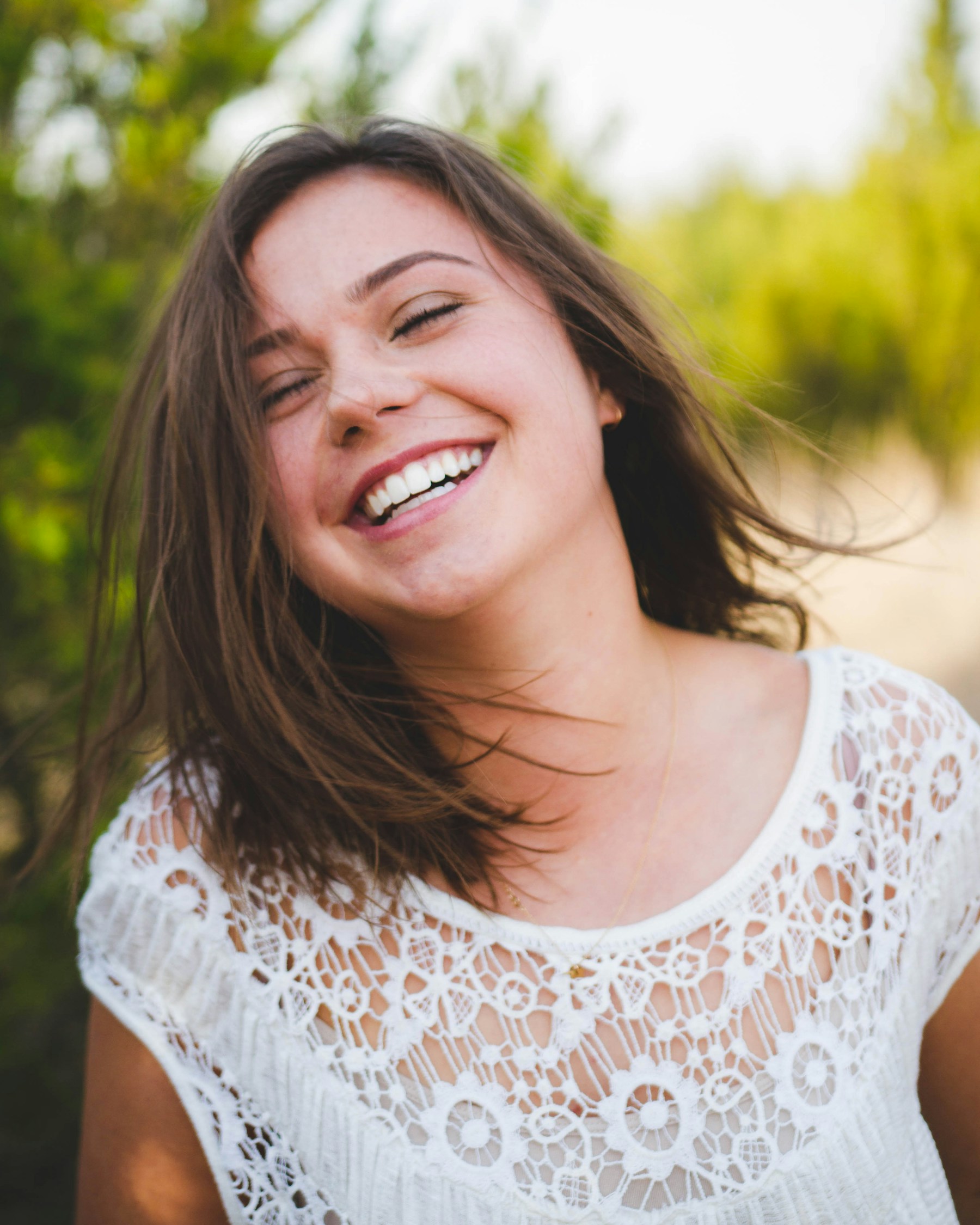 A woman sharing a relaxed, joyful smile outdoors